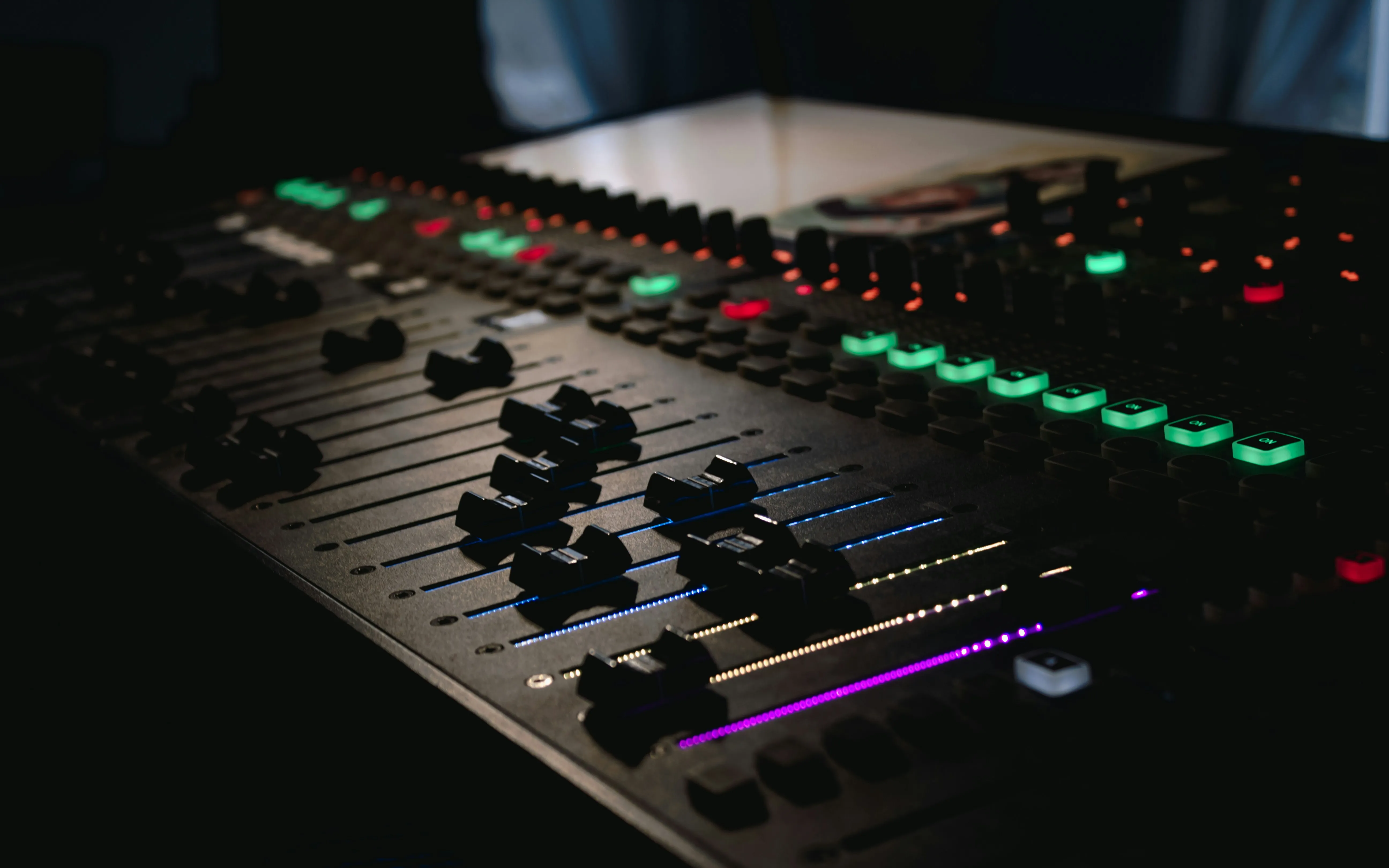 Dj's Mixing console with bright buttons make sounds on dark background. Sound engineer inside party